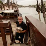 El historiador Ramón Jiménez Fraile posa con su libro a bordo de la réplica de la nao Victoria en río Guadalquivir en Sevilla. EFE /Julio Muñoz