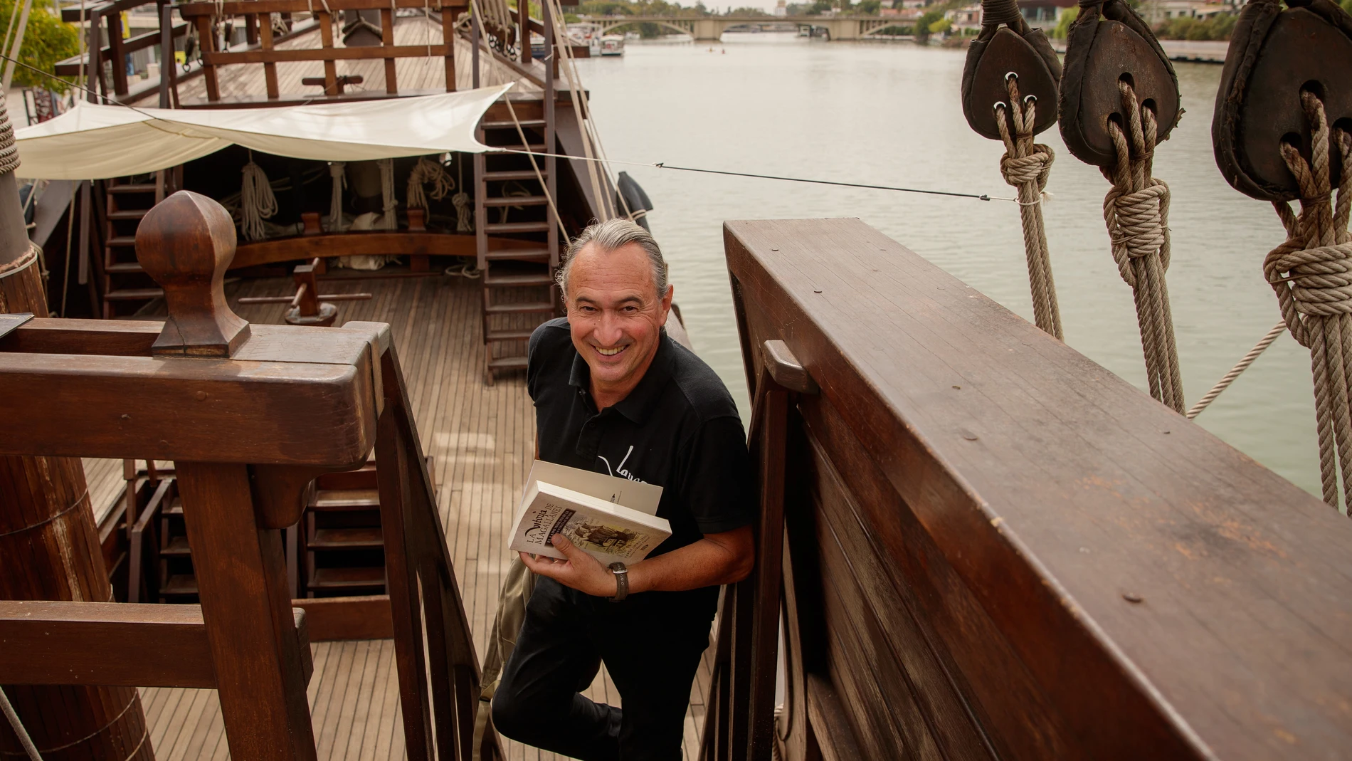 El historiador Ramón Jiménez Fraile posa con su libro a bordo de la réplica de la nao Victoria en río Guadalquivir en Sevilla. EFE /Julio Muñoz