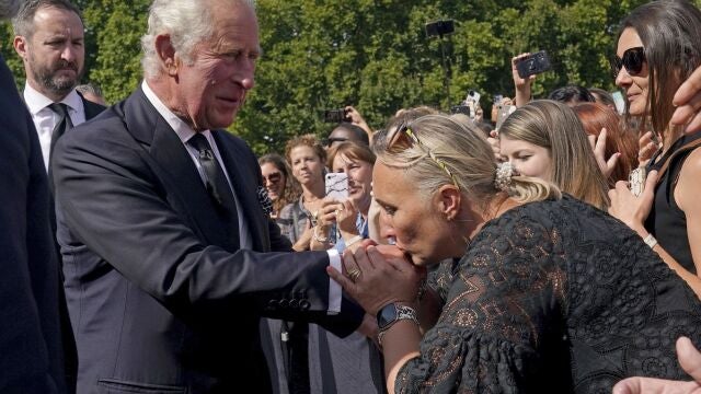 Una mujer besa la mano del nuevo monarca a su llegada al palacio de Buckingham
