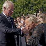 Una mujer besa la mano del nuevo monarca a su llegada al palacio de Buckingham
