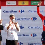 El ciclista belga Remco Evenepoel (d), virtual vencedor de la Vuelta 2022, acompañado por el presidente de Castilla y León Alfonso Fernández Mañueco (i) y por el exciclista ganador de un Tour de Francia Óscar Pereiro (2i), en el podio con el maillot rojo de líder tras la 20ª etapa de la Vuelta 2022 entre Moralzarzal y el Puerto de Navacerrada, este sábado. EFE/ Javier Lizón