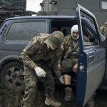 Un soldado ucraniano ayuda a un compañero herido en la carretera hacia Járkiv