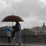 Dos personas caminan bajo sus paraguas en Sevilla en un día de lluvia. María José López / Europa Press