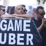 Un manifestante apoyado en el ataúd con el lema “Game Uber”. Joaquín Corchero / Europa Press