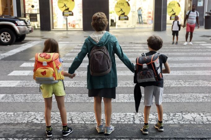 Una madre lleva a sus dos hijos al colegio