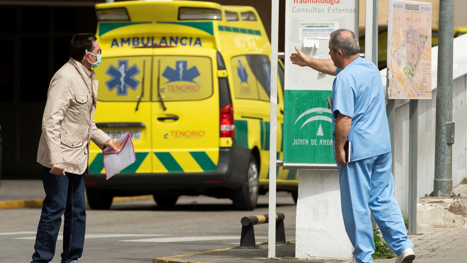 Una persona solicita información a un sanitario en el exterior del Hospital Universitario Virgen del Rocío de Sevilla