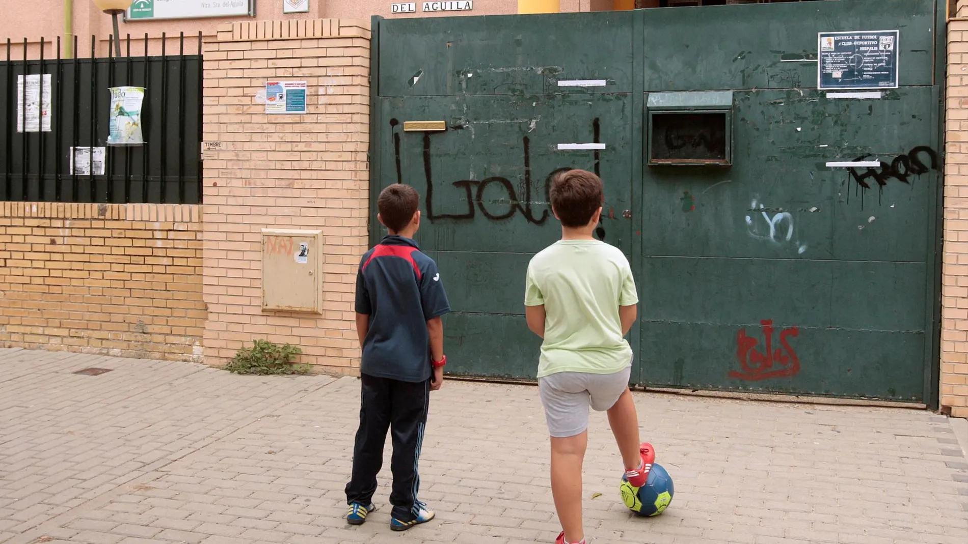 Dos niños frente a un colegio de Andalucía cerrado
