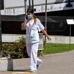 Una sanitaria habla por el móvil con mascarilla en el Hospital Virgen Macarena de Sevilla