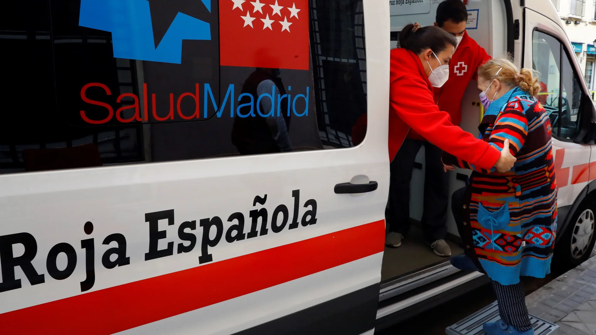 Miembros de la Cruz Roja ayudan a una vecina, antes de vacunarla contra la gripe, este jueves en la localidad madrileña de Aranjuez