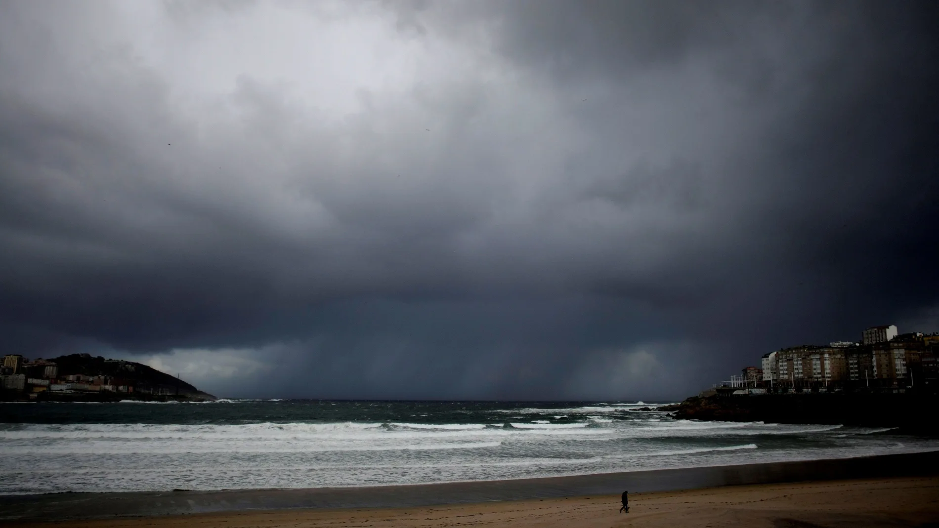 A CORUÑA.- Un hombre pasea a su perro por la playa del Orzán en A Coruña. EFE/ Cabalar