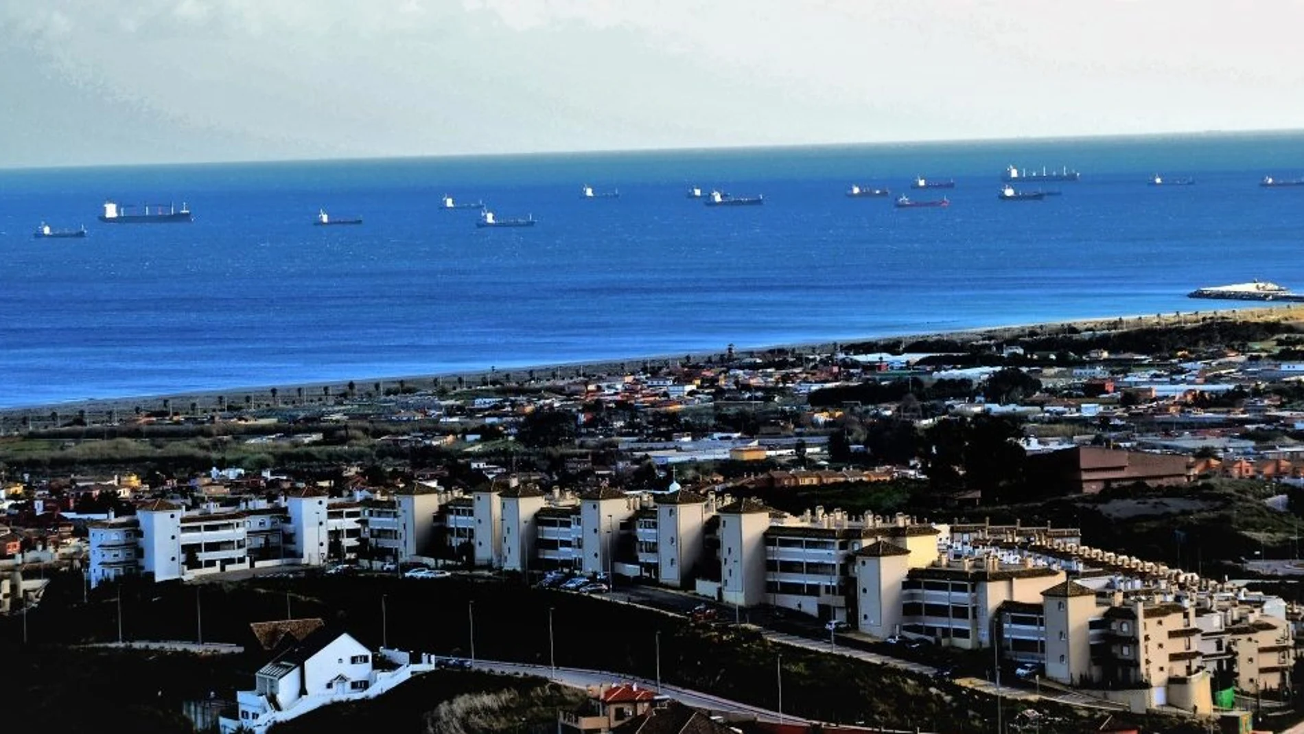 Vista de un rosario de buques que vuelve a Gibraltar, al fondo, desde el municipio gaditano de La Línea