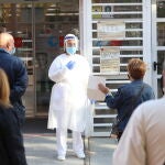 Una sanitaria sale a atender a las numerosas personas que hacen cola en un centro de salud de Madrid