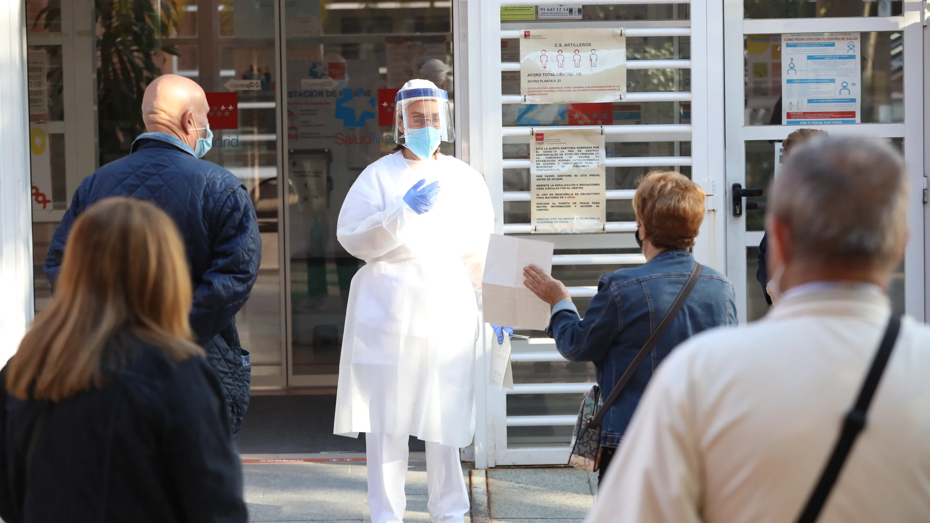 Una sanitaria sale a atender a las numerosas personas que hacen cola en un centro de salud de Madrid