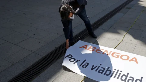 Un trabajador de Abengoa despliega un cartel donde se pide por la viabilidad de la empresa