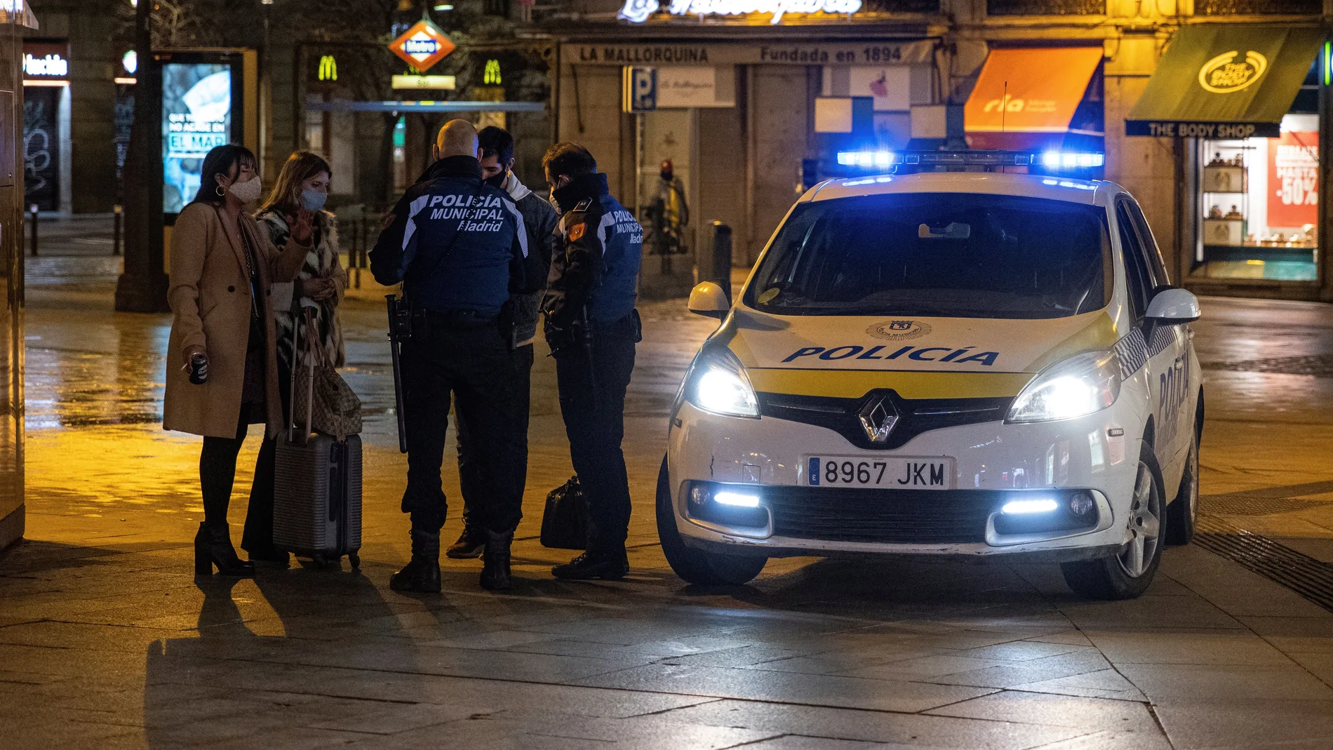 Dos policías municipales paran a tres viandantes en la madrileña Puerta del Sol, este lunes, pasadas las 22.00 horas, hora del nuevo toque de queda