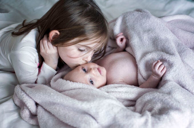 Una niña besa a su hermano recién nacido