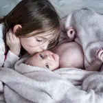 Una niña besa a su hermano recién nacido