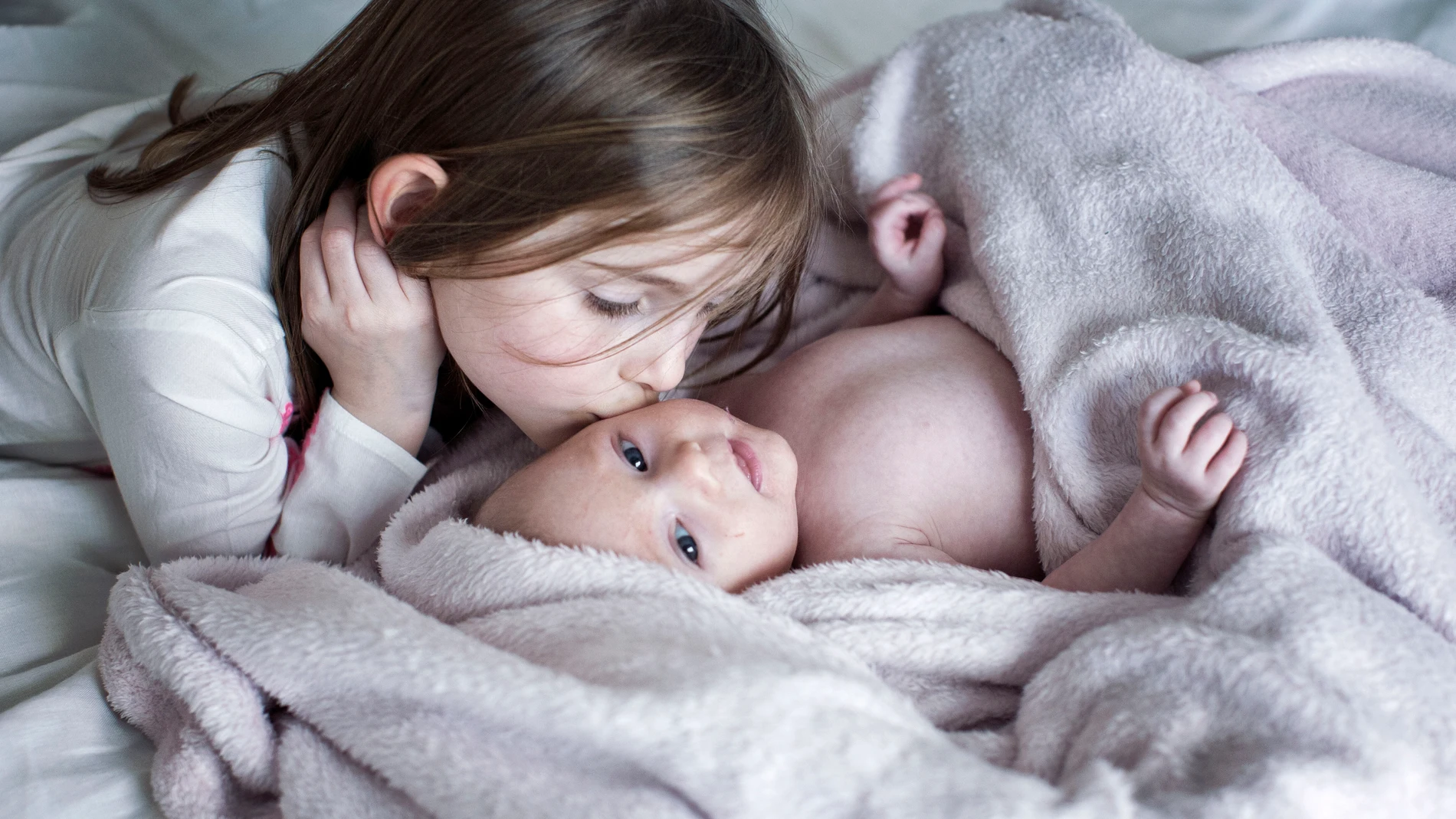 Una niña besa a su hermano recién nacido