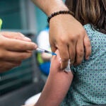 Un sanitario administra una dosis de la vacuna de Pfizer a una mujer en el Wizink Center