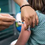 Un sanitario administra una dosis de la vacuna de Pfizer a una mujer en el Wizink Center