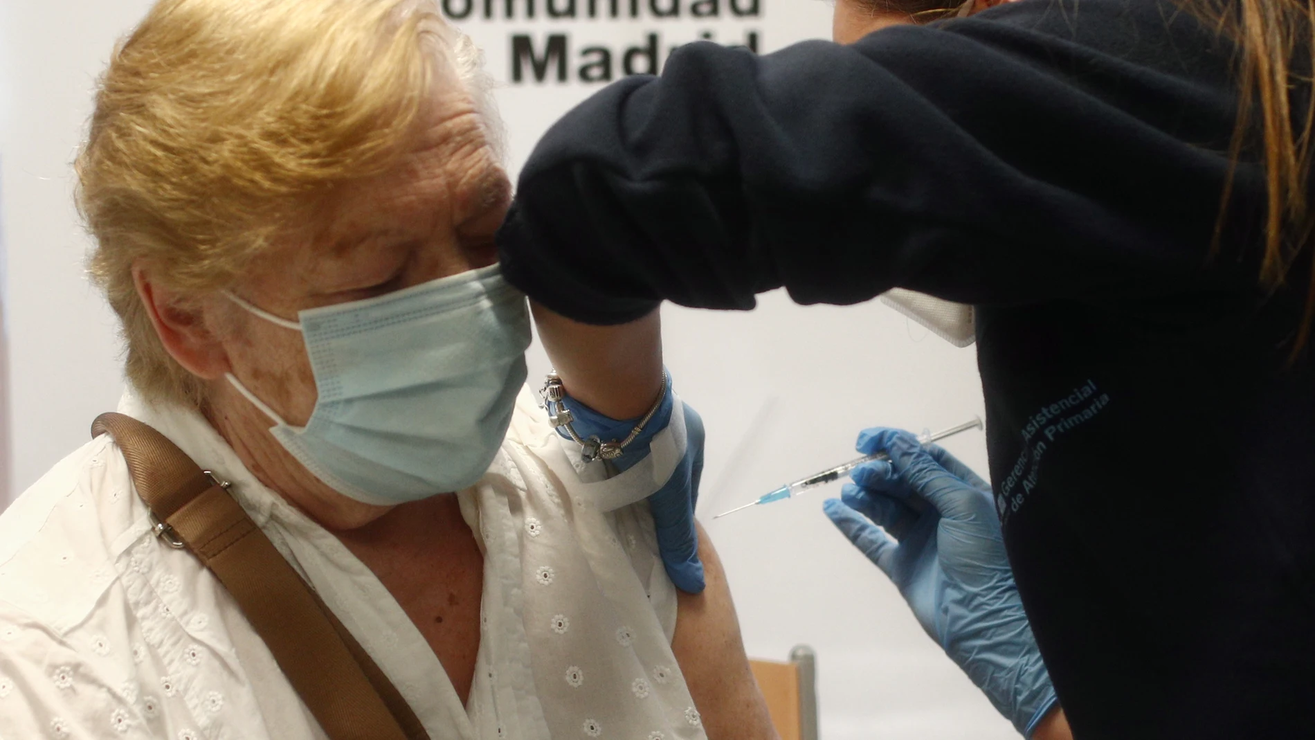 Una sanitaria inyecta la primera dosis de la vacuna de Pfizer contra el coronavirus a una anciana en el Centro de Salud Rejas, en Madrid