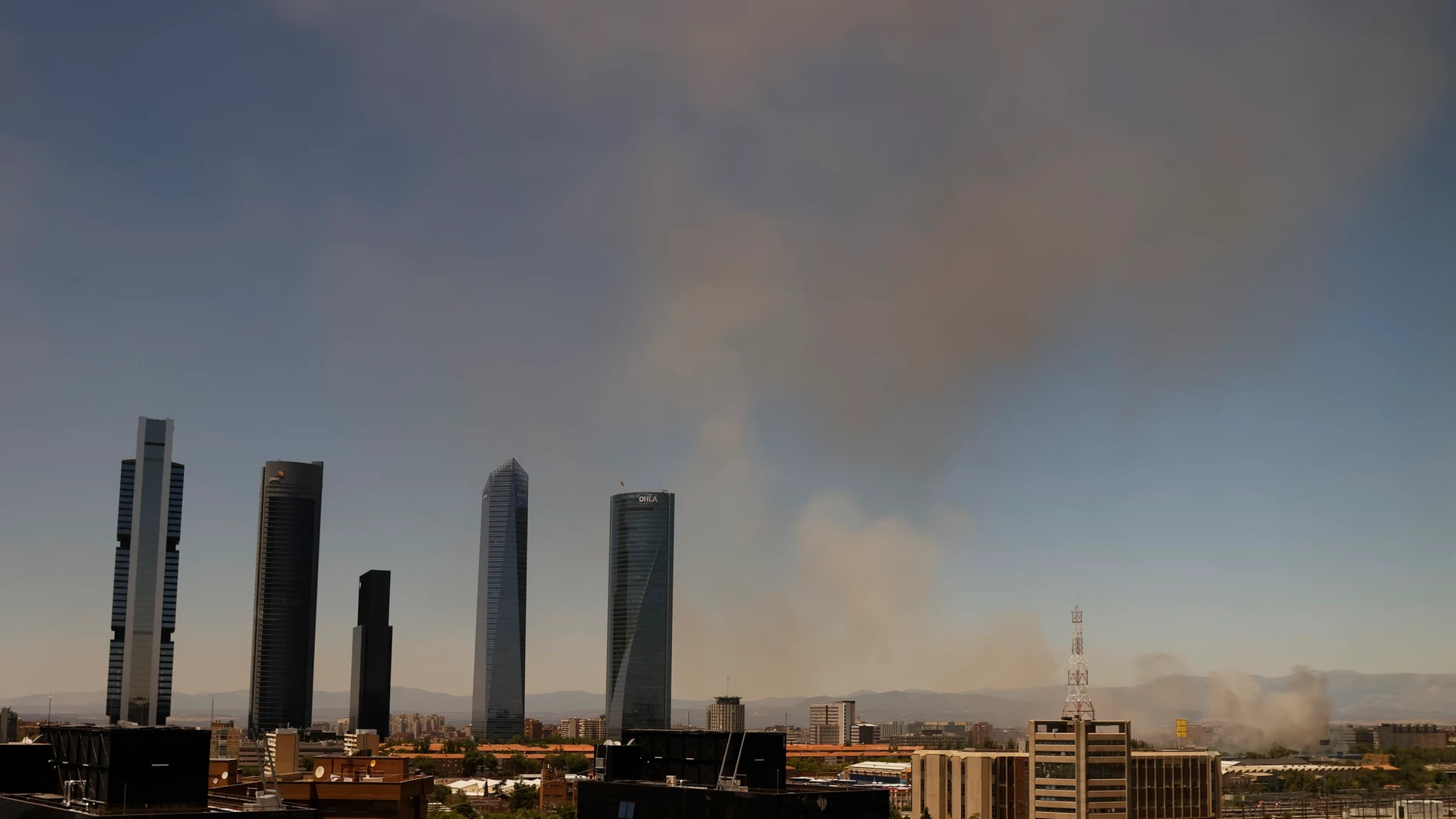 El humo se eleva sobre el fuego que se ha iniciado en una zona de descampado ubicada en la calle Juan Lozano, próxima al hospital de La Paz y a las Cinco Torres, por causas que se desconocen