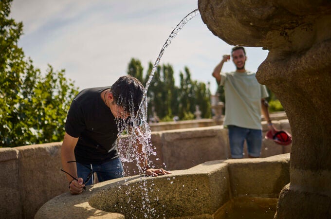 Personas intentan refrescarse en una fuente para combatir el calor en Madrid