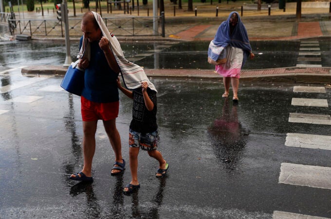 Varias personas se protegen de la lluvia en el distrito madrileño de Villaverde