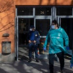 Un empleado de seguridad vigila una de las puertas por donde salen trabajadores sanitarios totalmente protegidos del centro de acogida San Isidro, en Madrid