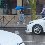 Una mujer con un paraguas pasa por una calle de Madrid