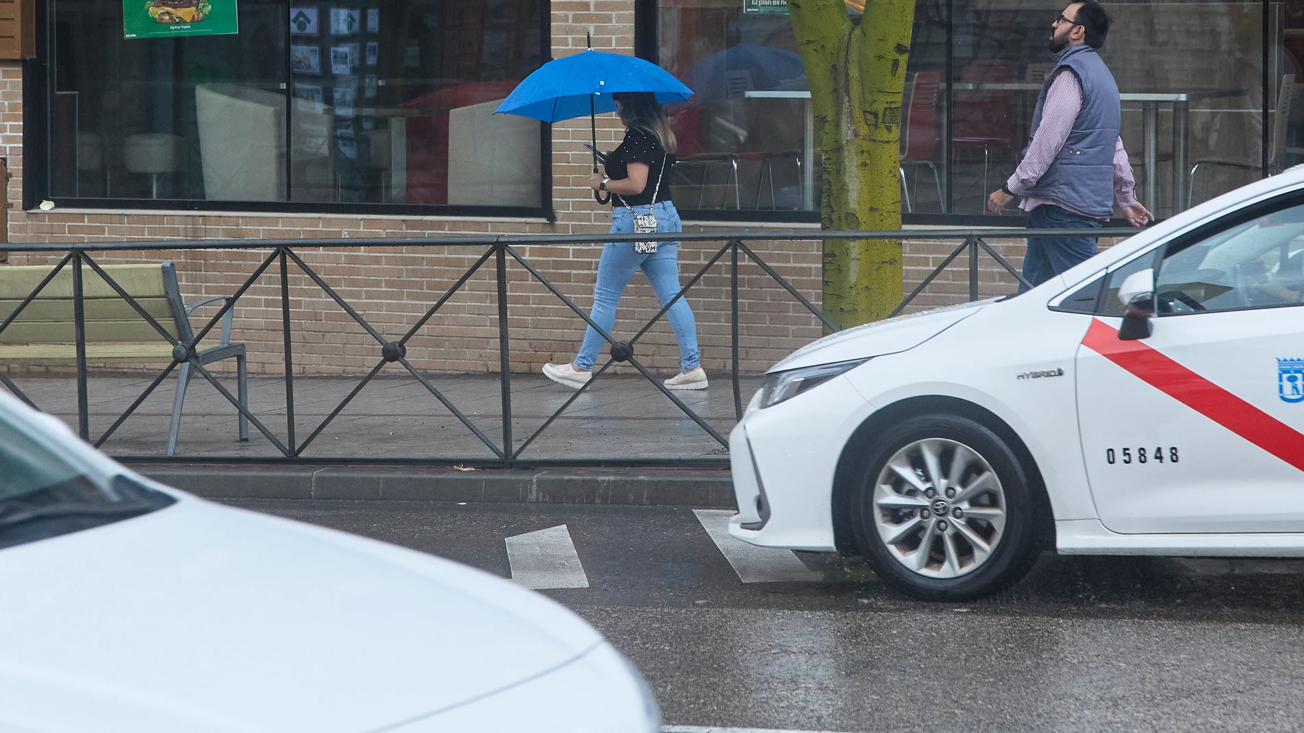 Una mujer con un paraguas pasa por una calle de Madrid
