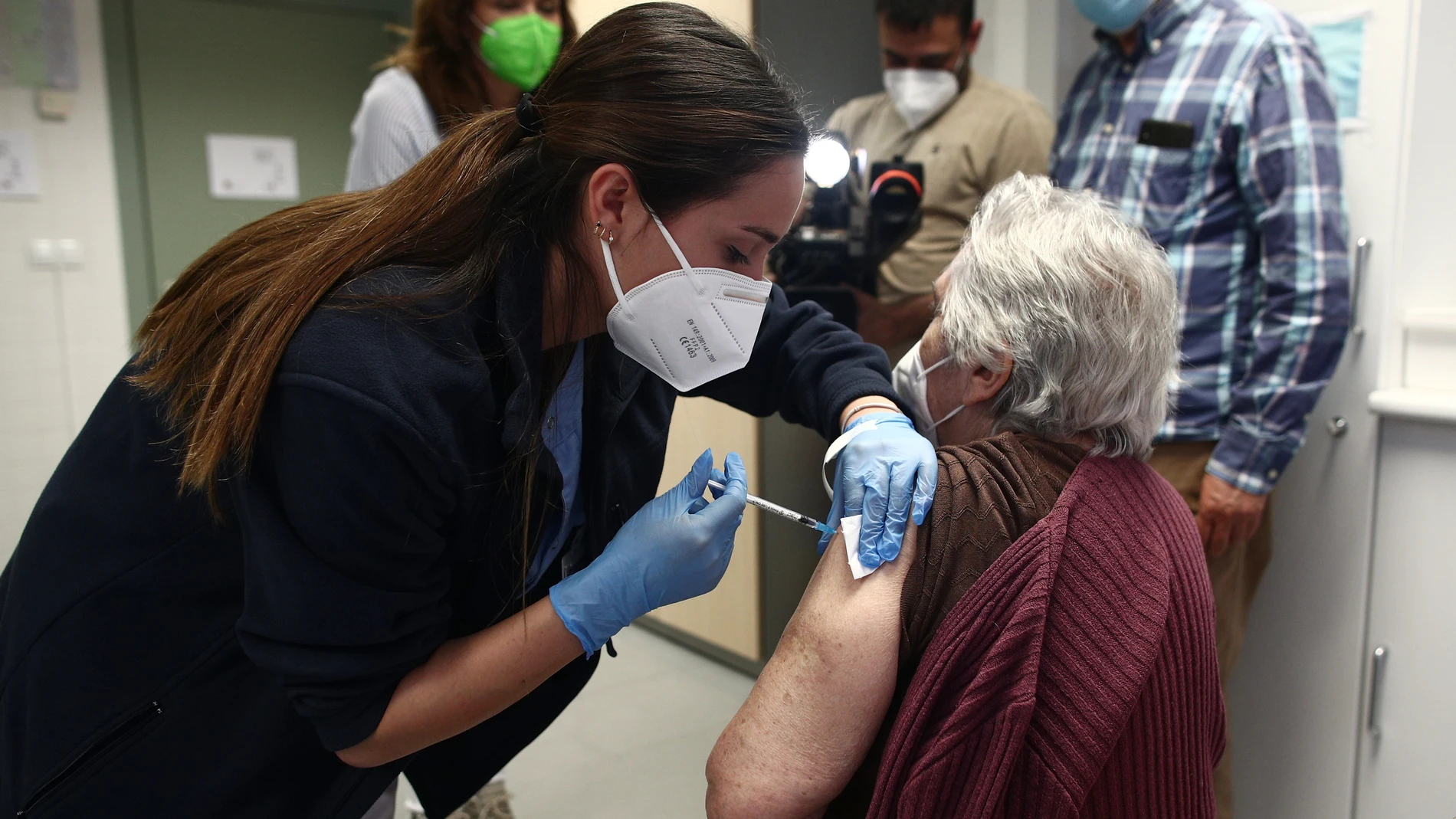 Una sanitaria inyecta la primera dosis de la vacuna de Pfizer contra el coronavirus a una anciana en el Centro de salud Rejas, en Madrid