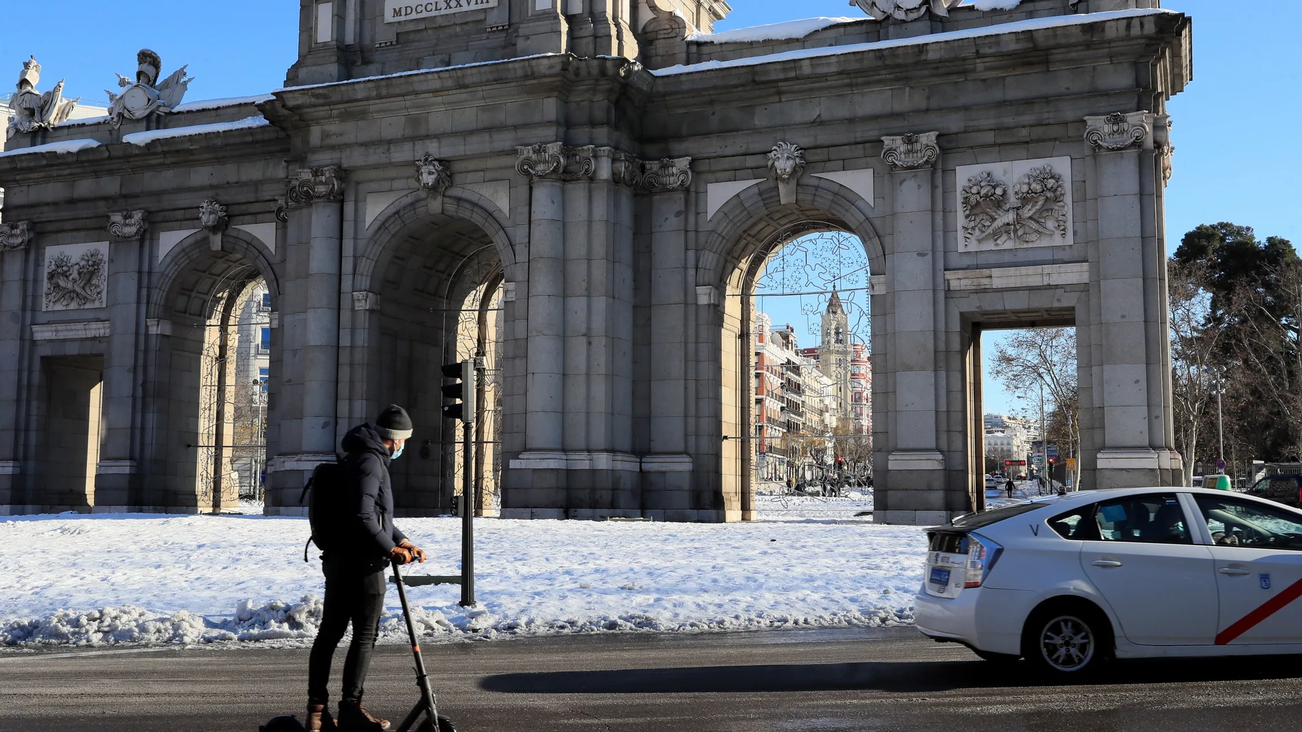 Un hombre circula con su patinete eléctrico por la madrileña calle Alcalá este lunes, tras el paso de la borrasca Filomena