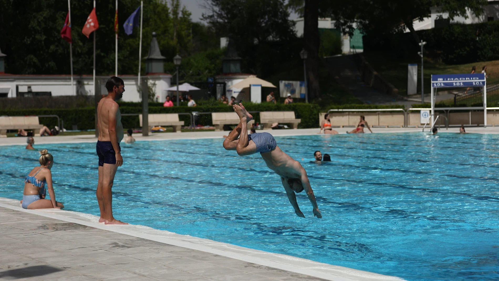 Un hombre se tira de cabeza al agua en una piscina municipal de Madrid