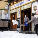 Personal de hostelería limpia de nieve las terrazas de los establecimientos en Madrid, este domingo