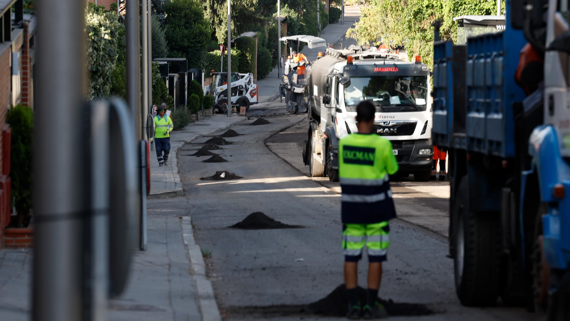Varios operarios trabajan en el asfaltado de un distrito madrileño