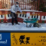 Un familiar colabora en la limpieza del hielo y la nieve en las inmediaciones del colegio Amadeo Vives tras la gran nevada por el paso de la borrasca 'Filomena', en Madrid
