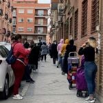 Un grupo de personas aguardan su turno para entrar al economato de Cáritas, en el distrito madrileño de Tetuán