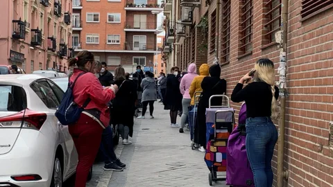 Un grupo de personas aguardan su turno para entrar al economato de Cáritas, en el distrito madrileño de Tetuán