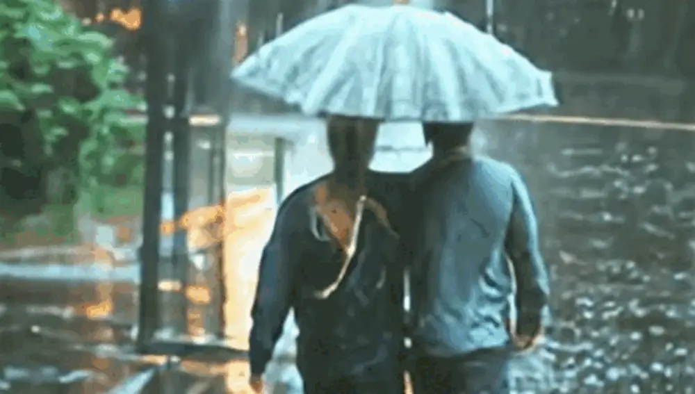 Una pareja joven caminando bajo una fuerte lluvia.