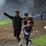 Un padre huye con su hija durante los incidentes en el Kanjuruhan Stadium en Indonesia