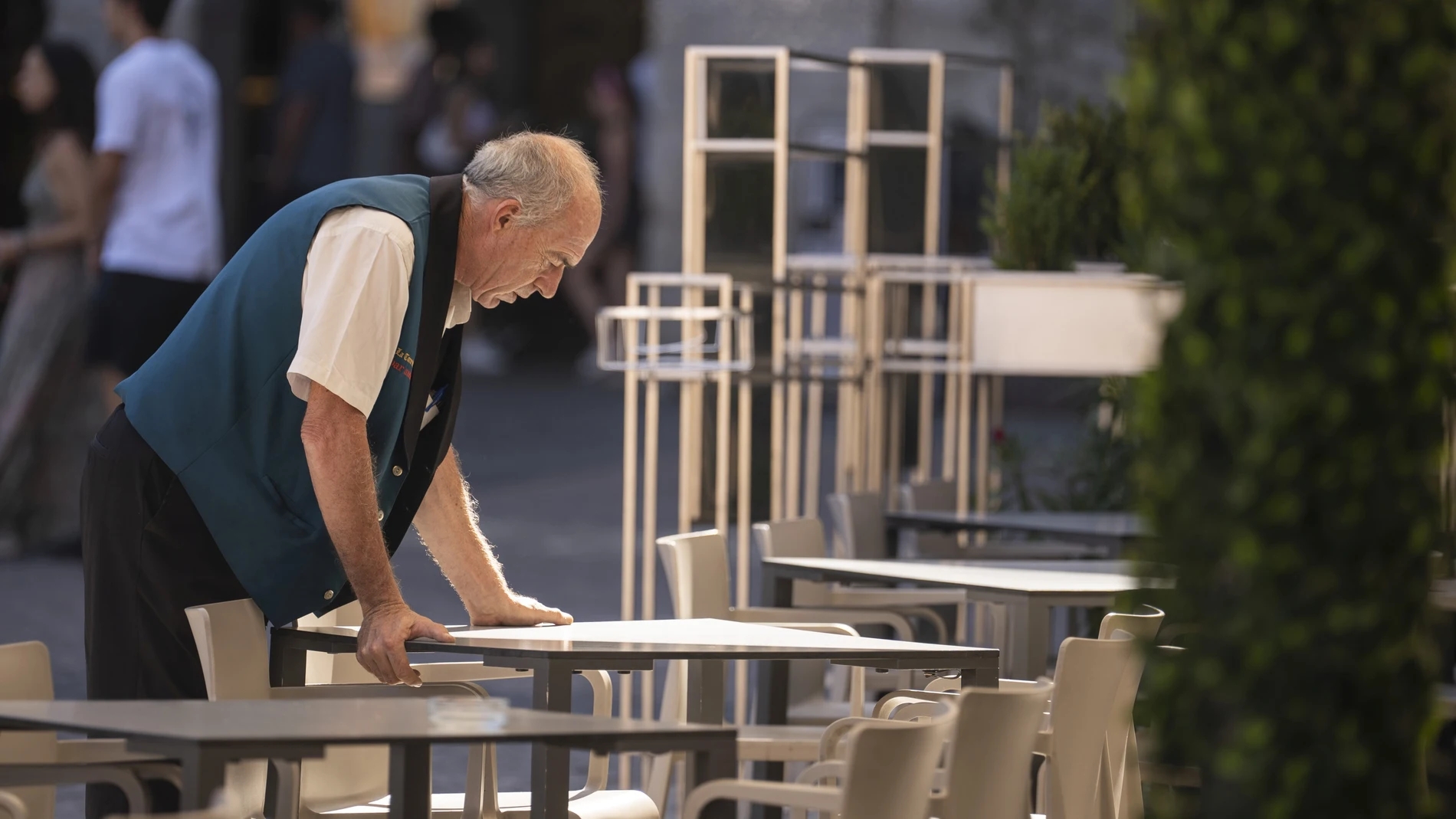 Un trabajador ordenando las mesas de una terraza en Madrid