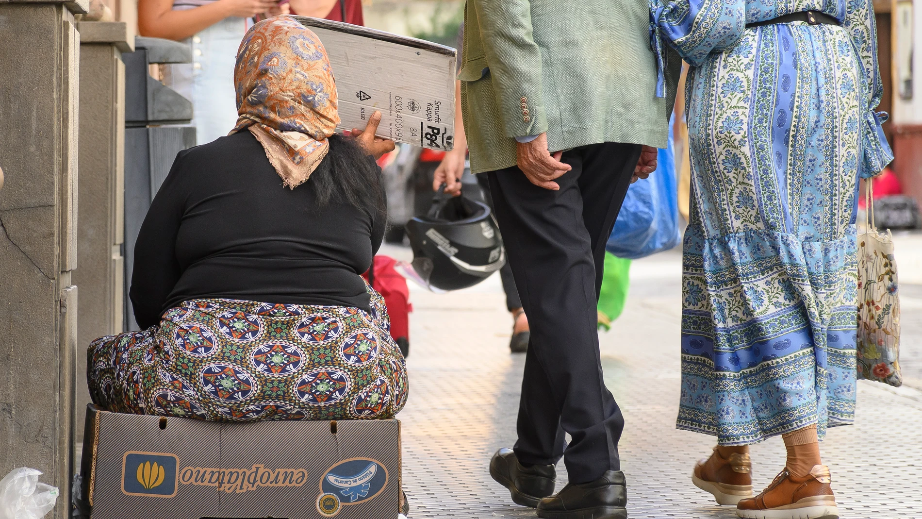 Una mujer sentada en una calle del centro de Sevilla pide dinero. EFE/ Raúl Caro.