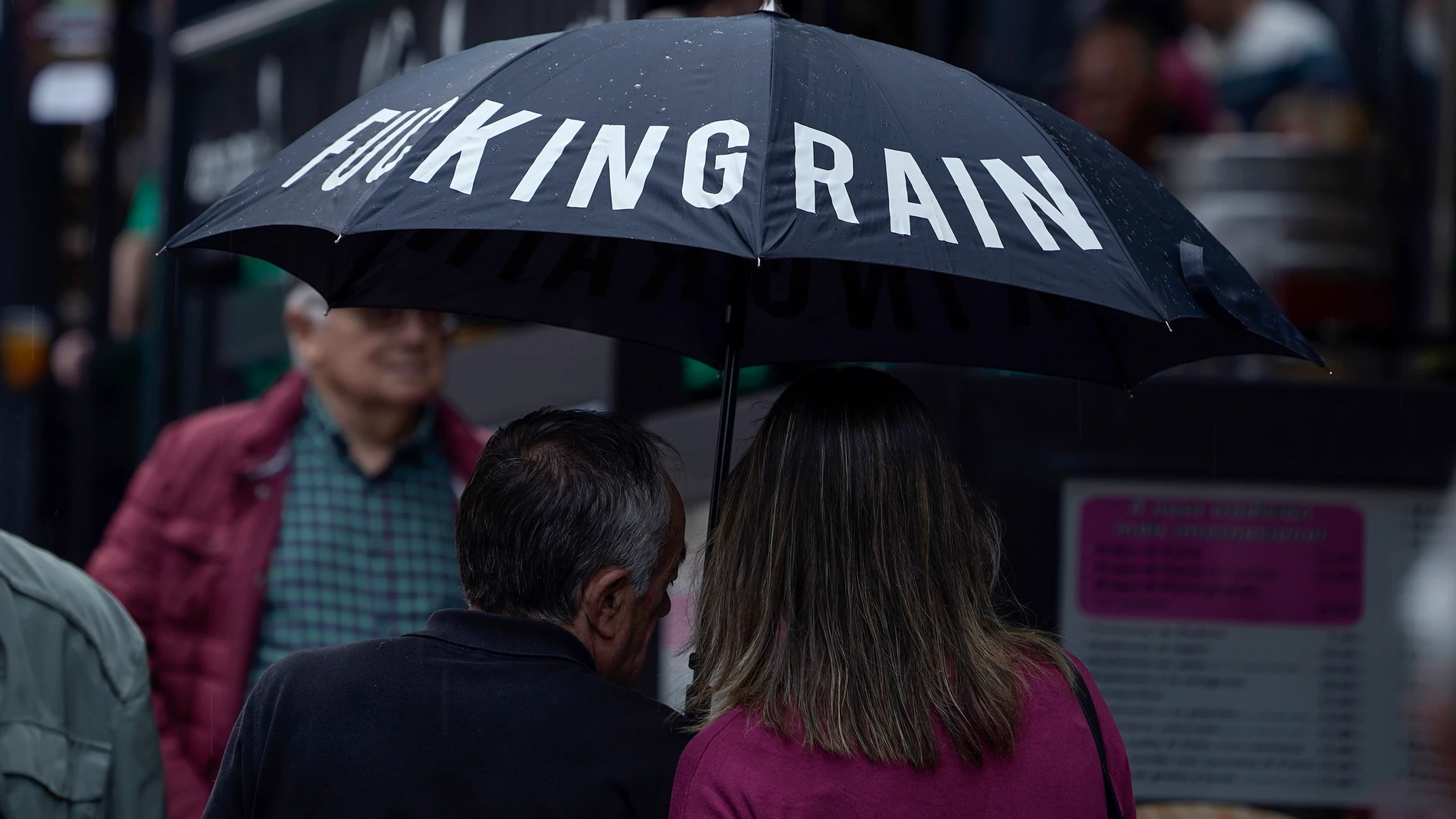 na pareja se protege de la lluvia con un paraguas en una calle del centro de Oviedo