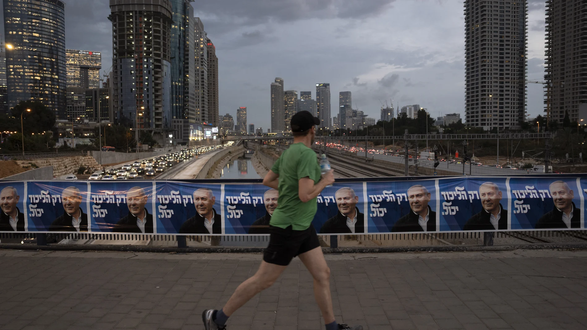 Un hombre corre junto a carteles electorales del líder del Likud, Benjamin Netanyahu