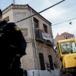 Un agente de Policía Nacional frente a una máquina retroexcavadora durante la demolición del edificio okupado ‘La Higuera’, en el barrio de Tetuán