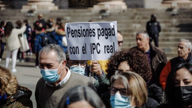 Un manifestante sostiene una pancarta durante una concentración convocada por la Unidad de Acción de los Movimientos de Pensionistas, ante el Congreso de los Diputados