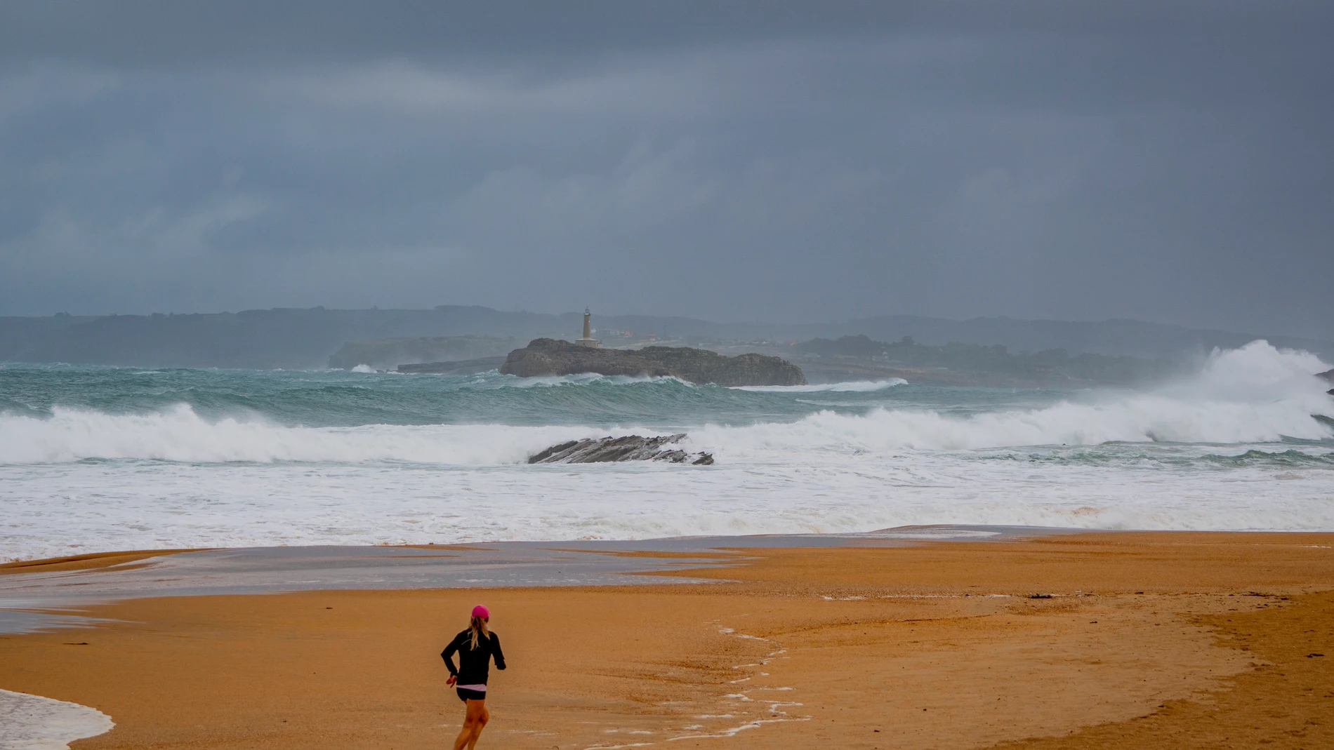 Una mujer corre por una playa de Santander, este viernes