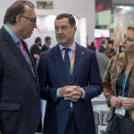 El presidente de la Junta de Andalucía, Juanma Moreno(c), charla con el consejero de Turismo, Arturo Bernal (i), y la consejera de Economía, Carolina España, este lunes en el pabellón andaluz de la WTM de Londres