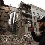 Un hombre toma una fotografía de Mikolaiv después de ser bombardeada por los rusos